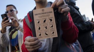 A man holds up a small piece of paper that reads 