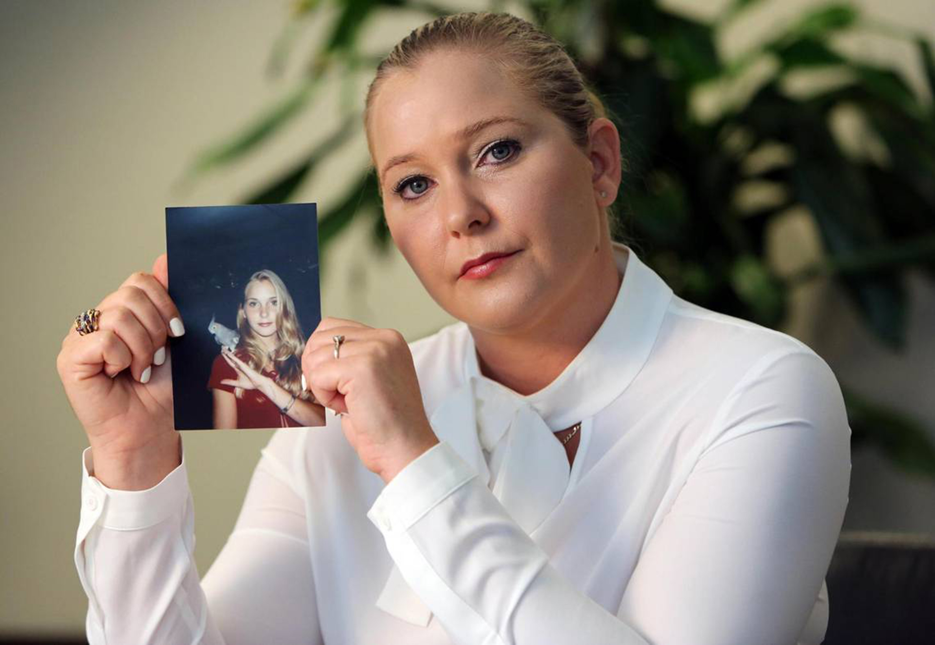Virginia Giuffre holding a photo of herself as a teenager.