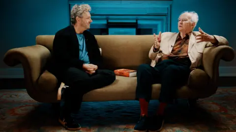 Will Carne Michael Sheen and Philip Pullman talking on a sofa 