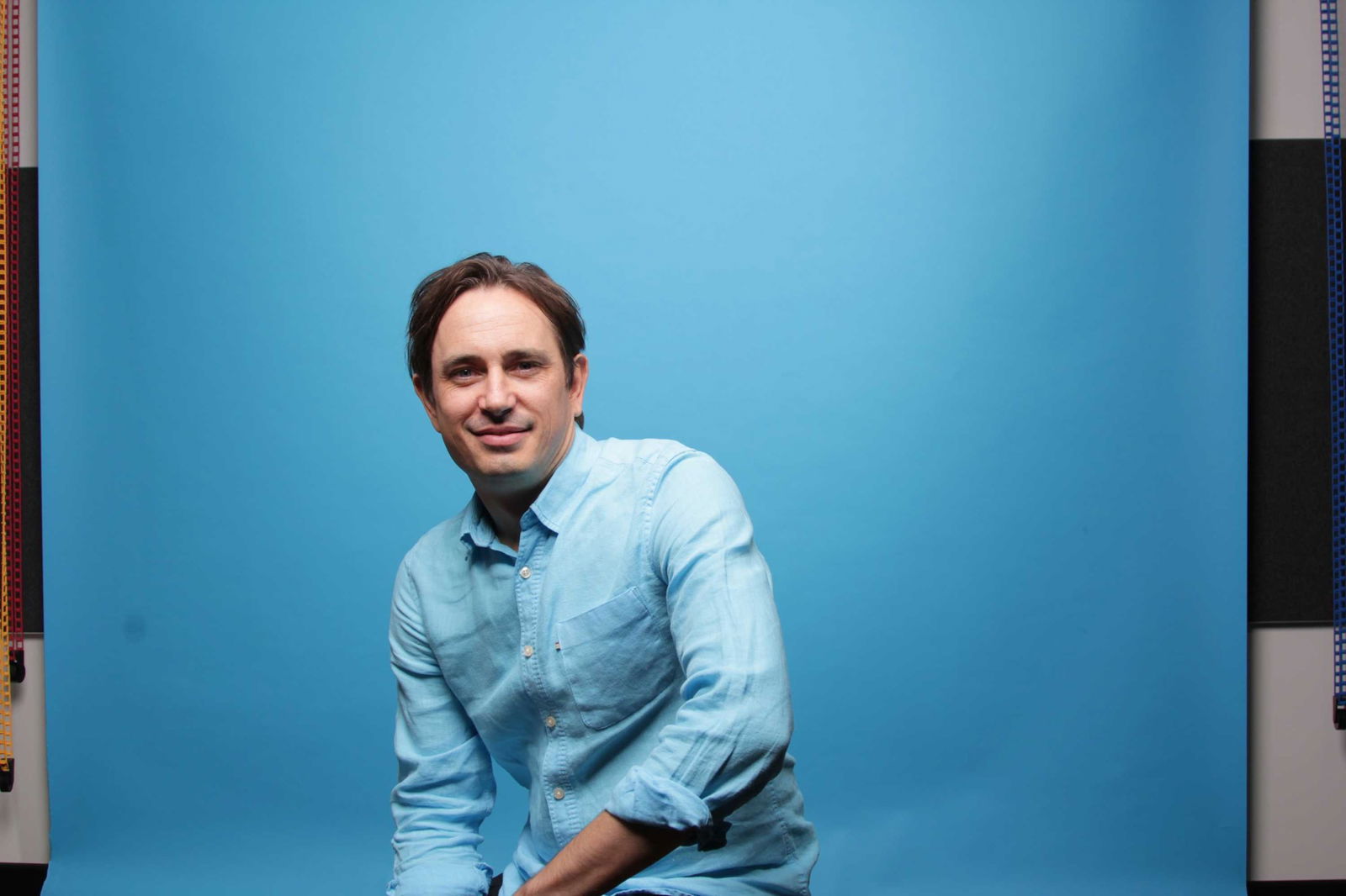A man sitting against a blue background