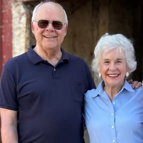 Casey Cep Photo showing Harper Lee's nephew, Dr Edwin Lee Conner on the left -- smiling & with sun glasses and wearing dark blue shirt and niece, Molly Lee in pale blue shirt, also smiling. Molly has grey short hair and is wearing large pearl earrings
