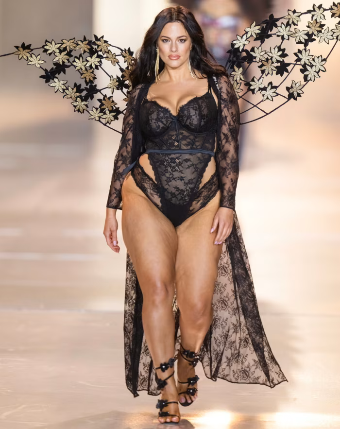 Ashley Graham walks the Victoria’s Secret 2024 runway in black lace lingerie with floral wings.